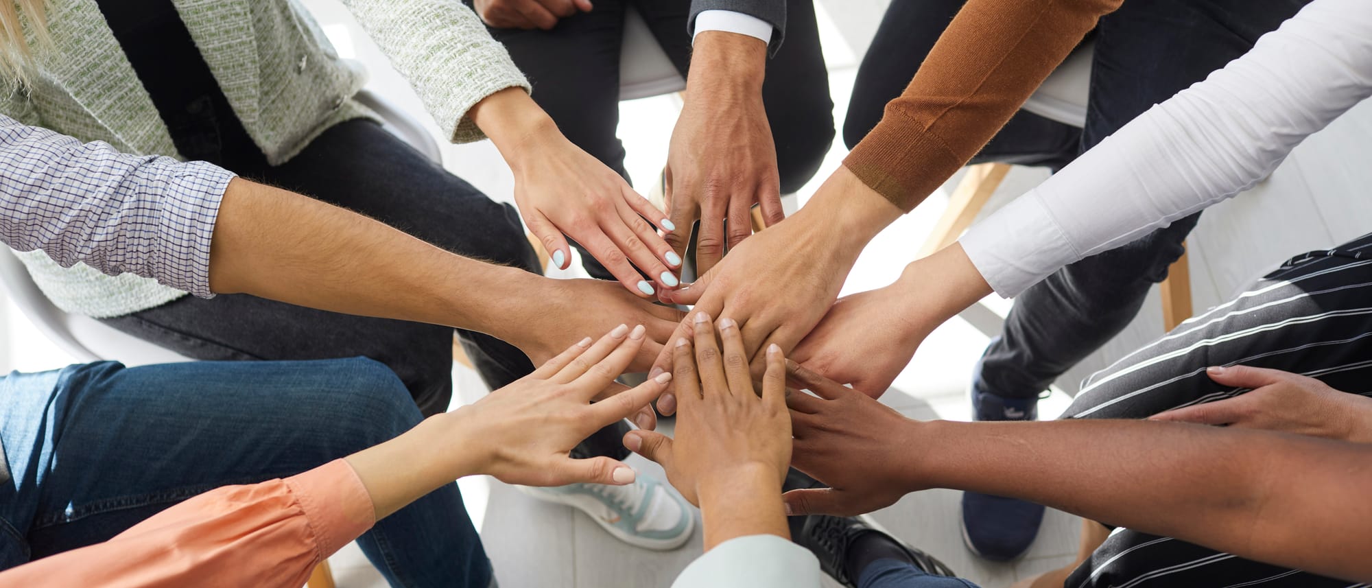 Mains de plusieurs personnes réunies en cercle